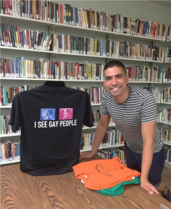 Gonzaba stands next to a shirt that reads "I see gay people."