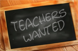 A cartoon chalkboard that reads "teachers wanted" in chalk