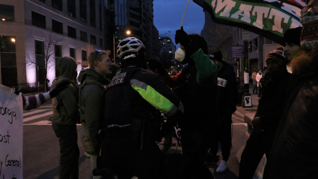 A DC police officer steps between opposing protesters.